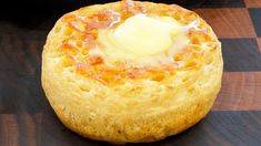 a close up of a pastry on a wooden surface with cheese and sauce in the center