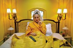 a woman sitting on top of a bed under a yellow blanket