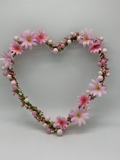 a heart shaped wreath with pink flowers and pearls