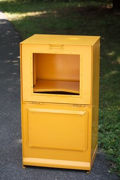 a yellow box sitting on the side of a road next to a grass covered field