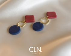 two blue and red earrings sitting on top of a white cloth