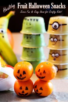 three oranges with faces painted on them sitting in front of some bananas and other fruit