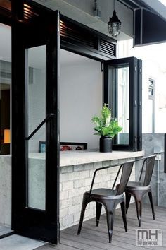 two chairs sitting on the outside of a building next to a counter with a potted plant in it