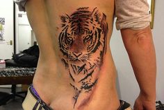 a woman with a tiger tattoo on her stomach and lower back, standing in front of a mirror