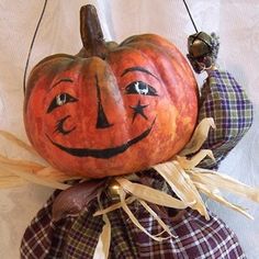 an orange pumpkin with a scarecrow's head hanging from the top of it