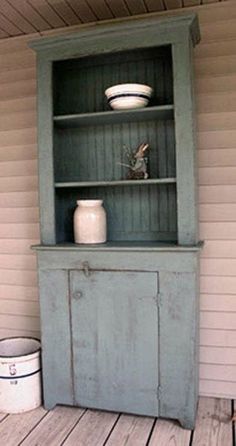 an old blue cabinet sitting on top of a wooden floor next to a white bucket