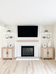 a living room with white walls and wood flooring has a flat screen tv above the fireplace