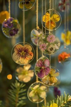 an arrangement of hanging glass ornaments with flowers in them and greenery on the side