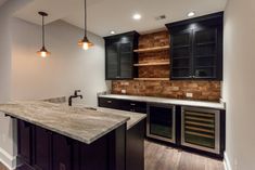 an empty kitchen with black cabinets and marble counter tops, along with wooden flooring