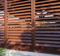 the side of a building with wooden slats on it and a plant next to it