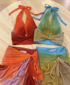 four different colored bikinisuits with ties tied around them on a white table top