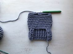 a crocheted object is sitting on a table next to a green knitting needle