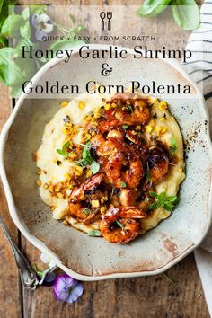 a white bowl filled with mashed potatoes and shrimp on top of a wooden table