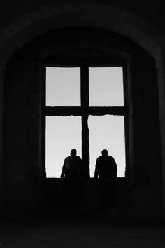 two people standing in front of a window