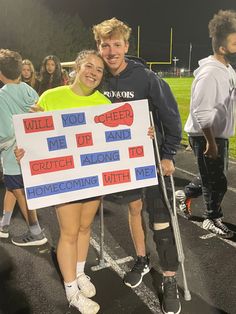 a man and woman holding up a sign on the side of a football field at night