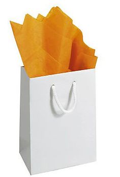 a white shopping bag with orange tissue paper inside and handles on the front, sitting upright against a white background