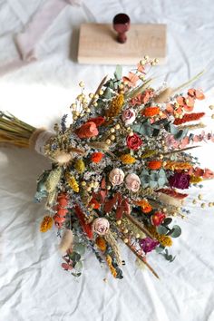 a bunch of dried flowers sitting on top of a white sheet next to a wooden block