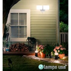 a house that is lit up at night with some plants in the yard and lights on