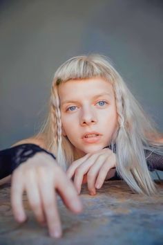 a woman with long blonde hair leaning on a table