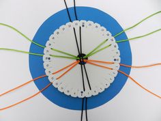 a white clock with orange and green hands on a blue circle that is connected to wires