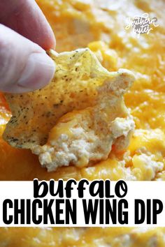 a hand dipping a tortilla chip into a cheesy chicken wing dip