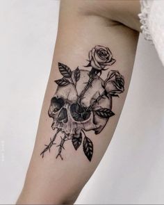 a black and white photo of a skull with roses on it's arm,