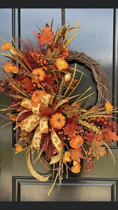 a wreath with orange and yellow flowers on the front door is decorated with fall leaves