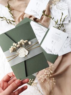 a person holding an envelope with flowers on it and some cards in front of them