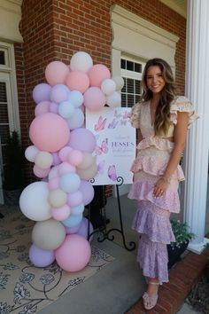 a woman standing in front of a sign with balloons