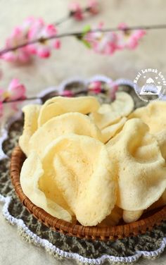 some kind of food that is in a basket on a table with flowers behind it