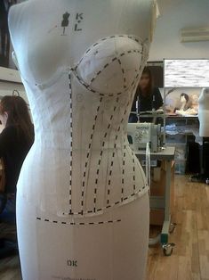 a woman is working on a dress made out of paper and fabric with lines drawn across it