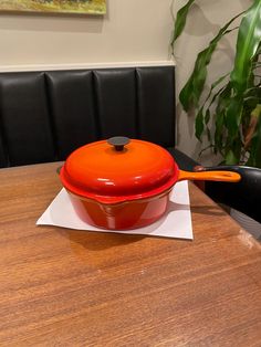 an orange casserole sitting on top of a wooden table next to a pot