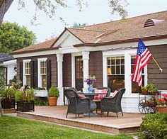 a patio with chairs, table and an american flag on the back wall in front of it