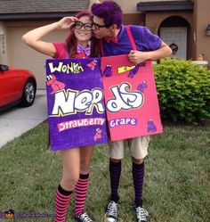 two people dressed up in costumes standing next to each other holding signs that say nerds