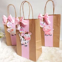 three brown paper bags with pink bows and farm animals on them are sitting on a white surface