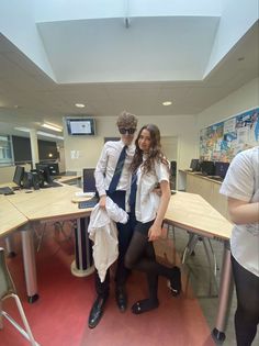 two people are posing for a photo in an office setting with desks and chairs