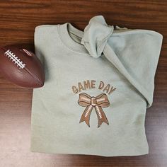 Cozy game day sweatshirt. Embrace the football vibes and enjoy the football season in this soft and cozy crewneck! Wear it at kid's football game, college football game, NFL football game, at home, at the cabin, camping, at a bonfire, or any time all season long! Makes for a perfect, cozy addition to your collection or as a gift! Football, game day, fall, autumn, cozy, sweatshirt, crewneck bonfire, fall leaves, bow. Minimalist style. Specs: Loose fit. 8-ounce, 50/50 cotton/poly. Double-needle st Football Embroidered Sweatshirt, Fall Game Day Sweatshirt With Embroidered Graphics, Team Spirit Sweatshirt With Letter Embroidery For Game Day, Football Game College, Game Day Sweatshirt, Fall Friends, Football Sweater, Football Game Outfit, Cabin Camping