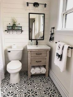 a white toilet sitting next to a sink in a bathroom under a mirror and towel rack