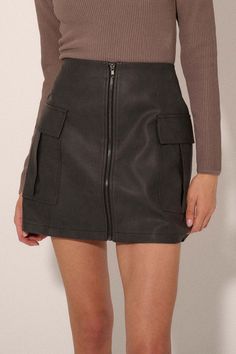 Faux leather mini skirt. Full front zipper closure. Flap cargo pockets. Thigh length. A-line silhouette. Relaxed fit. 55% Cotton, 45% PU. Imported. Designed in LA. Model wears size S. Fall Mini Skort With Pockets, Fall Mini Length Skort With Pockets, Edgy Skirt With Pockets For Fall, Edgy Mini Skirt With Pockets For Night Out, Fitted Leather Mini Skirt With Pockets, Faux Leather Skirt With Pockets For Night Out, Fall Mini Skirt With Pockets For Night Out, Edgy Mini Skirt With Zipper Closure For Fall, Fitted Cargo Skirt With Pockets For Night Out