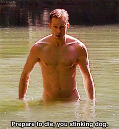 a shirtless man is wading in the water with his hand on his hip