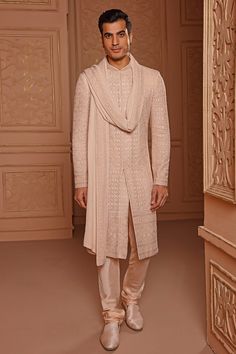 a man standing in front of a doorway wearing a beige outfit