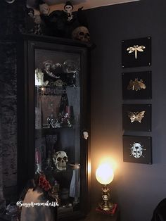 a dark room with skulls on the wall and a lighted lamp in front of it