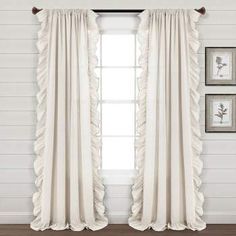 white curtains with ruffles hanging on the window sill in front of two framed pictures