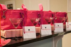 pink bags and wine glasses are lined up on the counter in front of each other