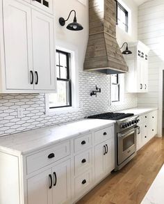 a kitchen with white cabinets and an oven above the stove, is shown in this image