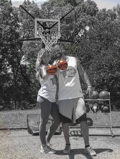 a man and woman standing next to each other holding basketballs in front of a basket