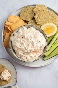 a plate with crackers, celery, and dip on it next to crackers