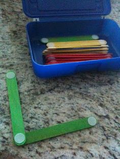 a blue container filled with pops sticks next to a pile of green stick markers on top of a counter