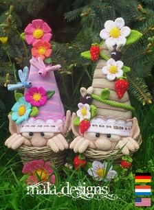 two small knitted gnomes with flowers on their heads, sitting in the grass