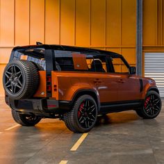 an orange and black suv parked in a parking lot next to a garage door with yellow doors